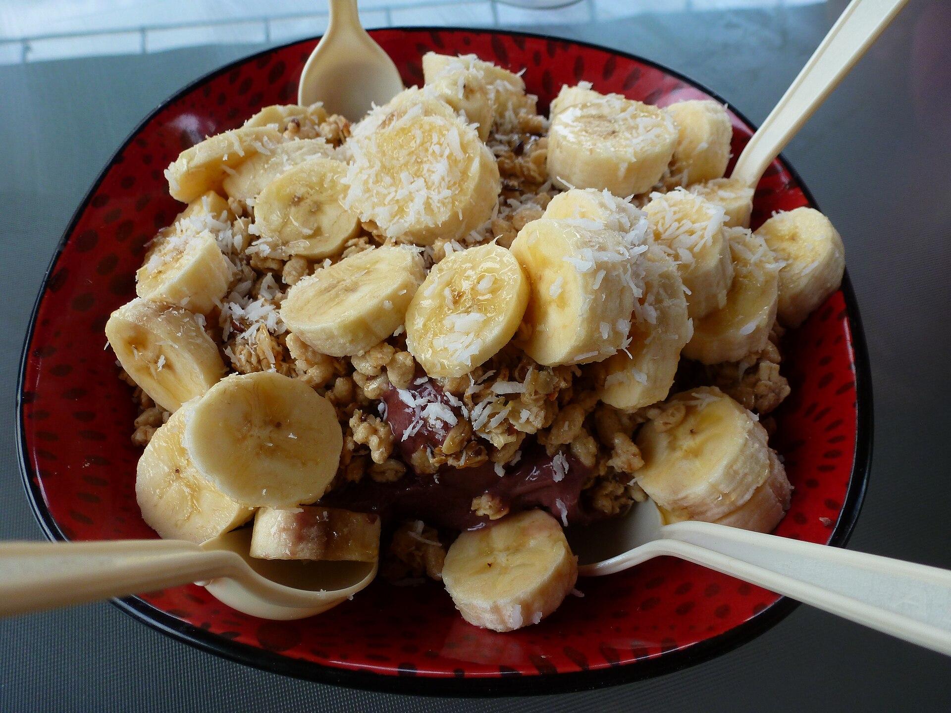 Cliente entregando açaí pela janela do balcão de açaiteria de bairro com luz natural — atendimento pessoal local